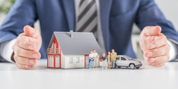 Insurance house, car and family health live concept. The insurance agent presents the toys that symbolize the coverage.