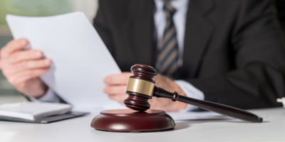 Judge gavel with lawyer working on legal document in background